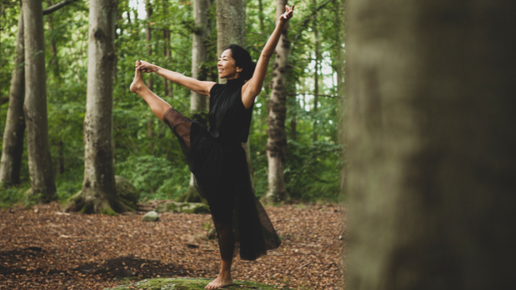 Monika Björn gör en yoga pose på en sten i skogen 